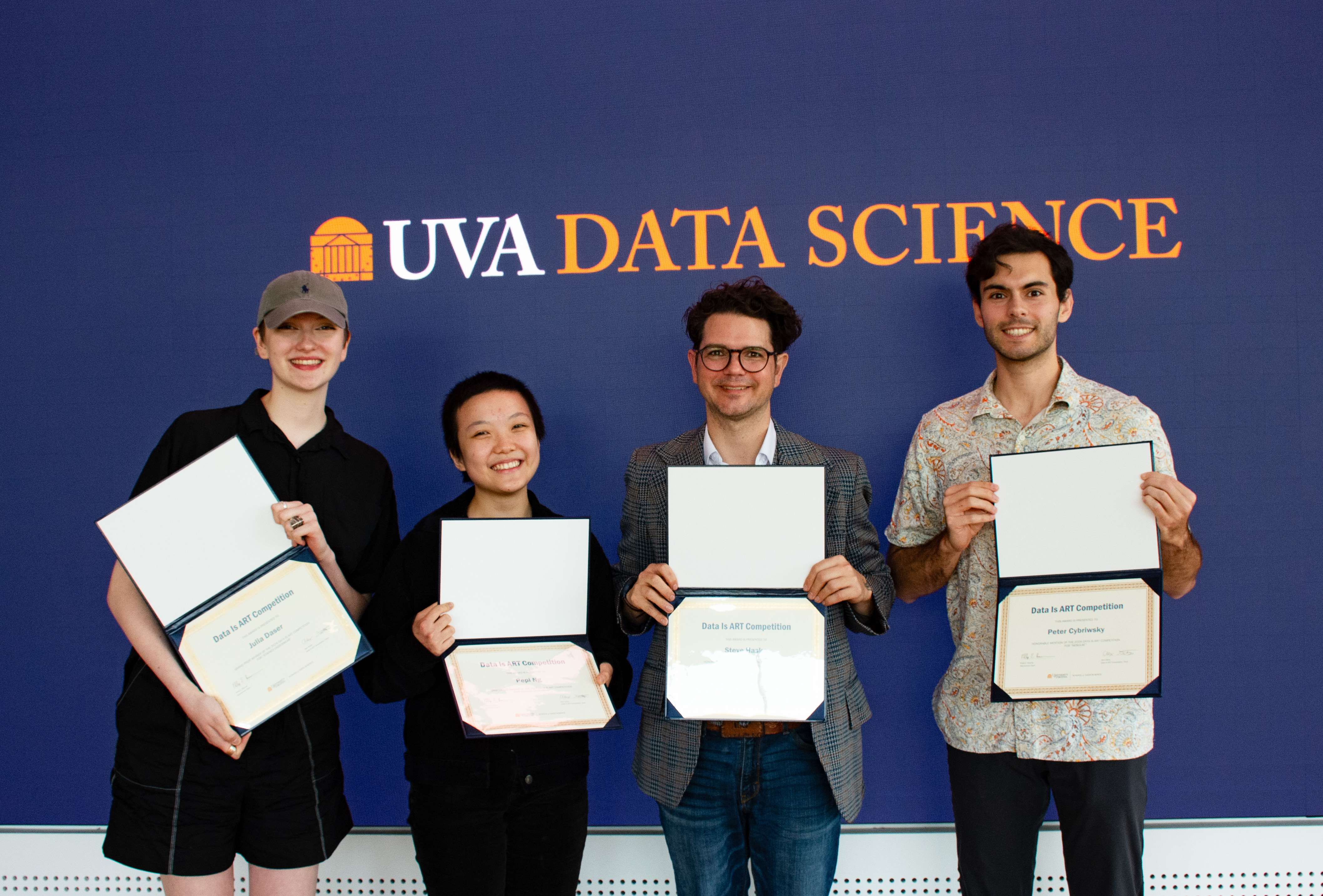 Four individuals standing in front of a UVA Data Science backdrop, holding awards from data competitions.