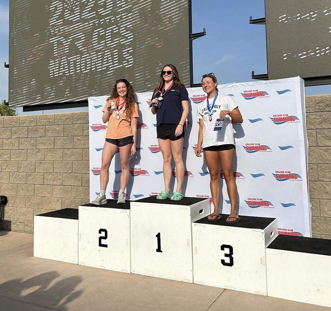 Elizabeth Miller poses on the second place podium step with other swimmers.