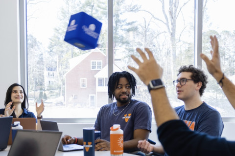 masters of data science students throwing and catching a cube in a conference room.