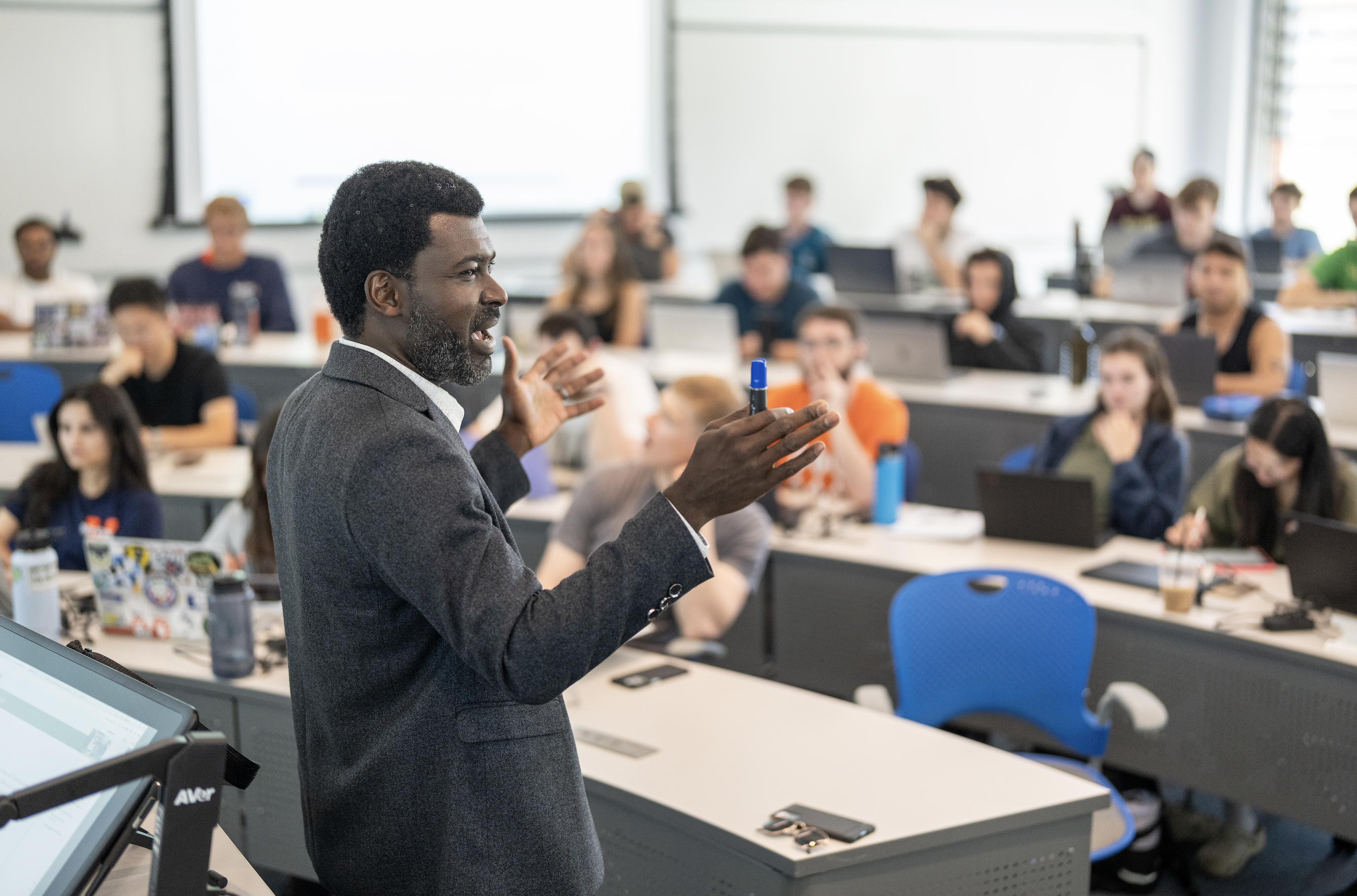Associate Professor of Data Science, Prince Afriyie, teaching his class with his hands palm faced up as he's talking.