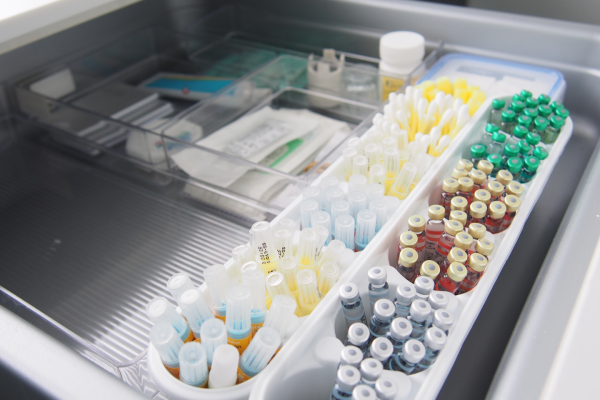Medical supplies in a drawer, showcasing organized test tubes with colorful caps, vials, and packaged items.