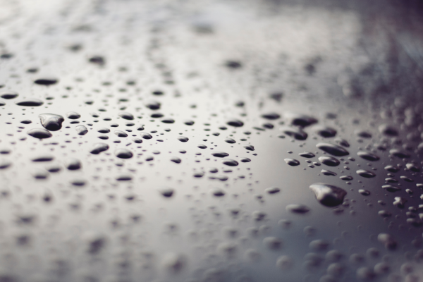 Close-up of water droplets on a smooth reflective surface, creating a textured pattern. 